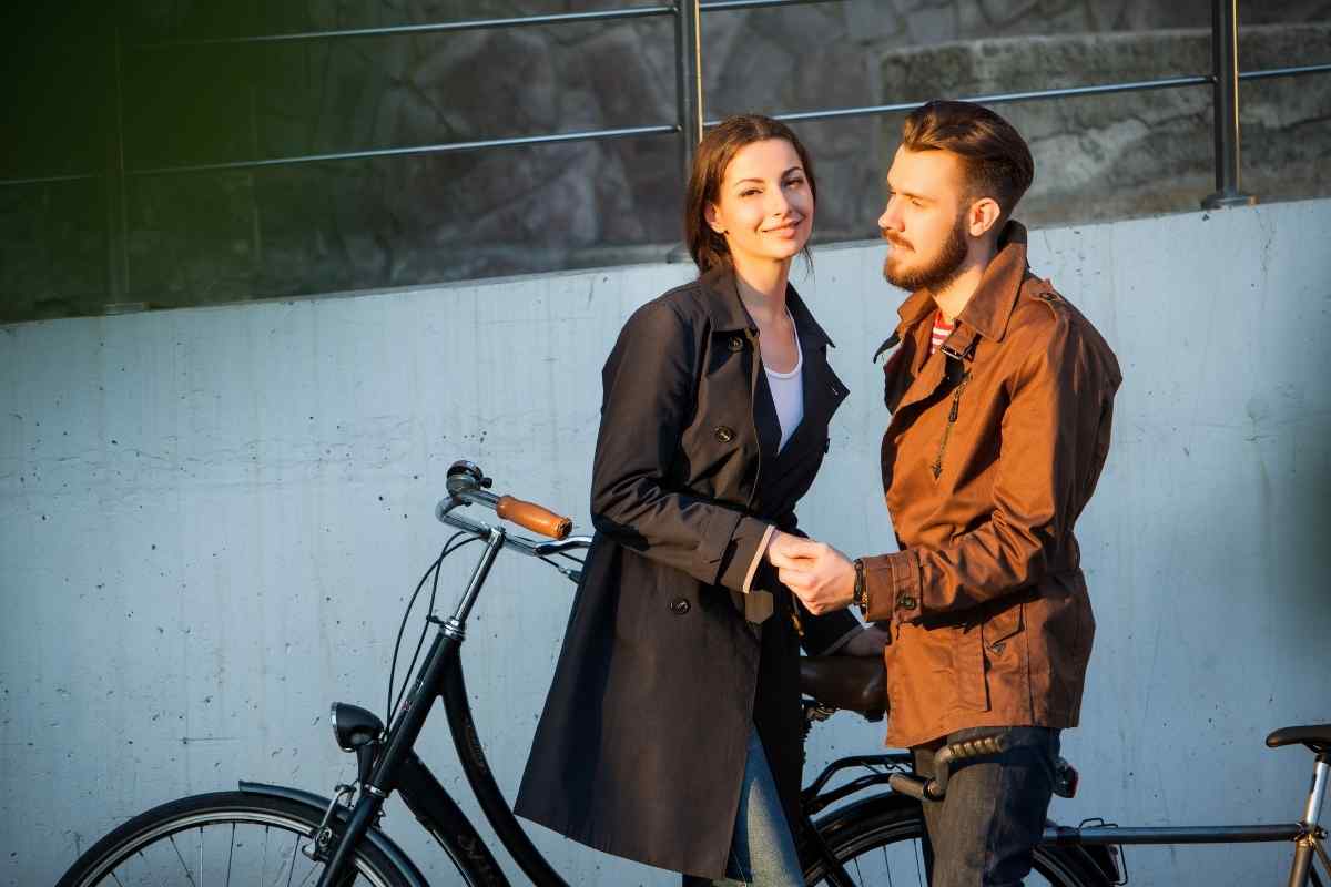 A man looking at his phone and a woman looking toward him with emotional distance evident between them, showing Aquarius withdrawal through disconnection