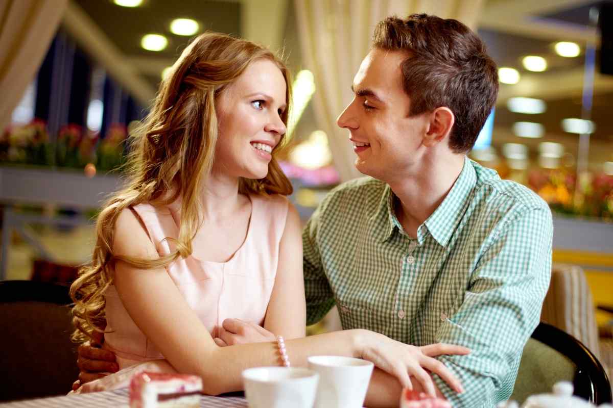 A woman leaning toward someone across a table, speaking candidly with a relaxed, open expression