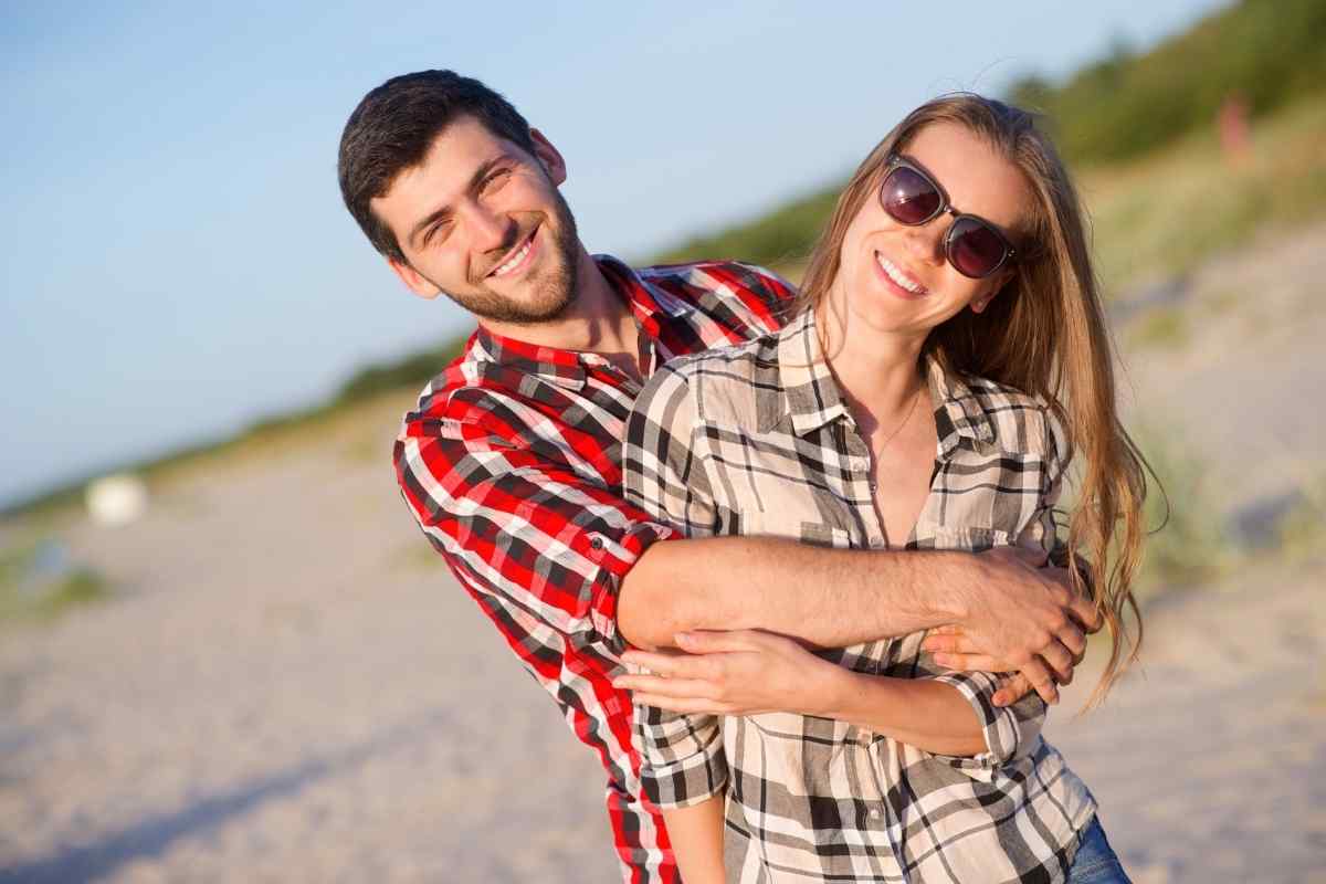 An Aquarius man and woman standing close together, both laughing easily and clearly comfortable in each other's space