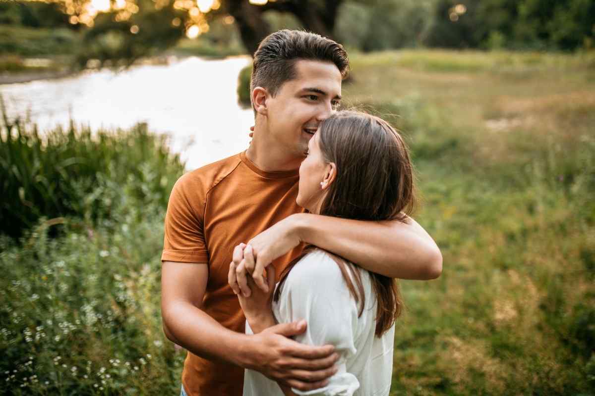 A couple laughing together outdoors, the woman confident and relaxed in her own energy