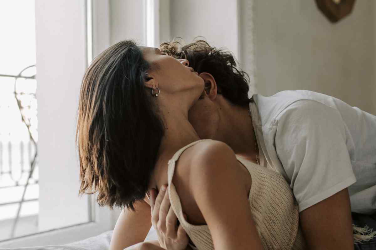 A couple close together in a warm, intimate setting, one partner gently and attentively touching the other's neck and face