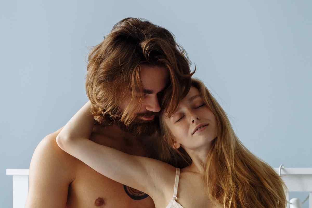A man with his hands on a woman's shoulders and the back of her neck, her posture relaxed and receptive
