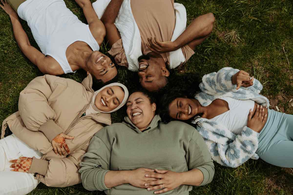 A group of friends lying together in a circle, laughing in the grass