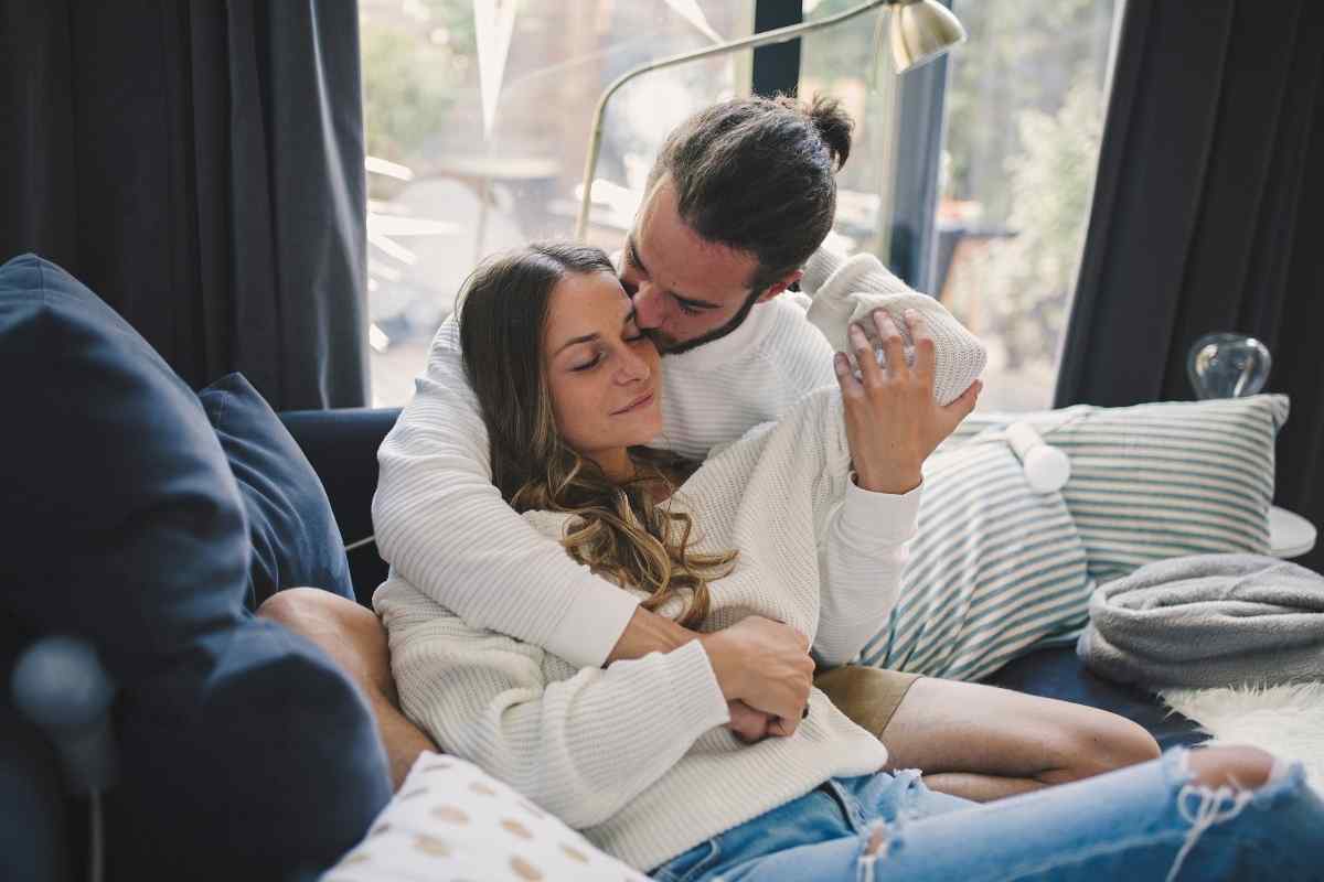A couple close together in a private, candlelit space, relaxed and entirely present with each other