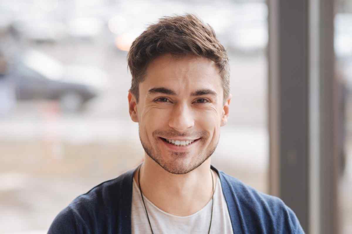 A confident man reading his phone with a relaxed, pleased expression in morning light