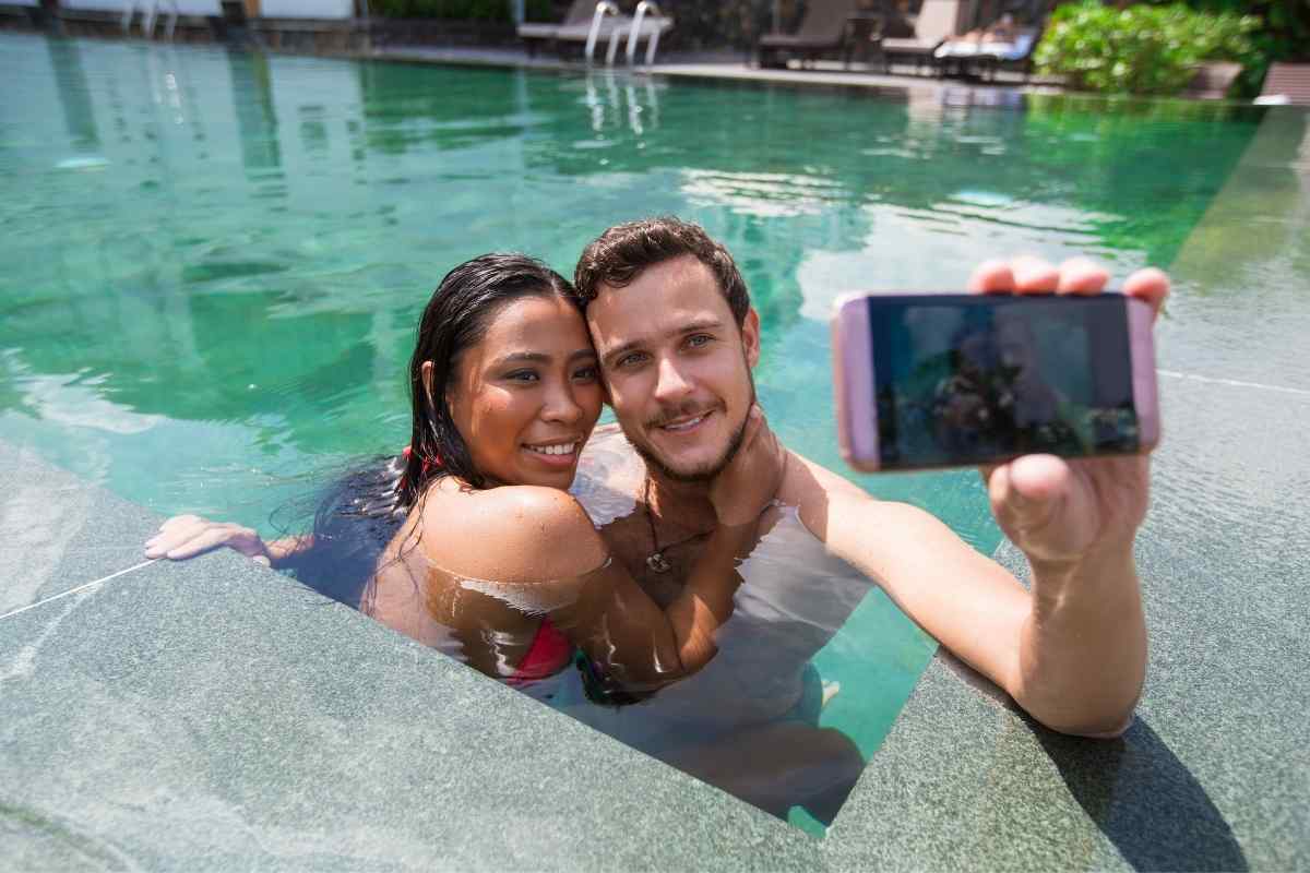 Two people sharing a relaxed morning, one passing a phone to the other with a smile