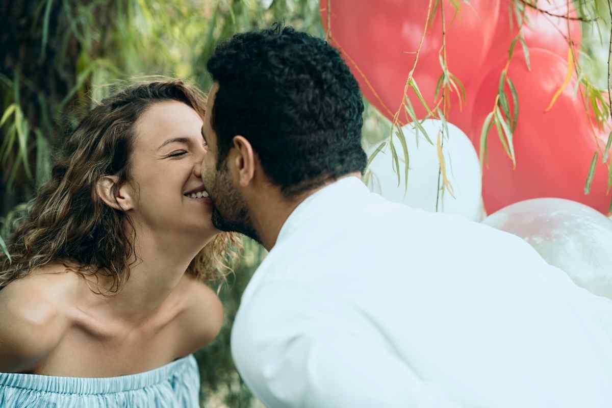 A couple close together, faces nearly touching, with warm candlelight in the background