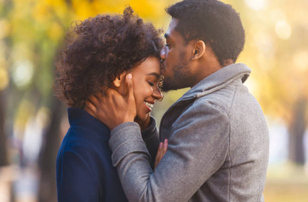 A woman and a Pisces man sharing a gentle forehead touch, eyes closed, a moment before a kiss