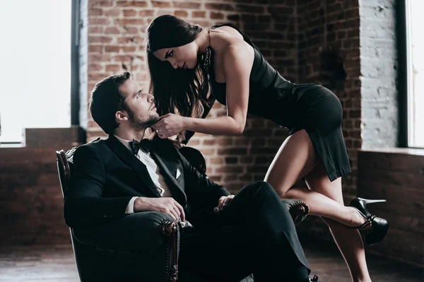A man sitting close to a woman on a park bench, their shoulders nearly touching as she laughs at something he has said